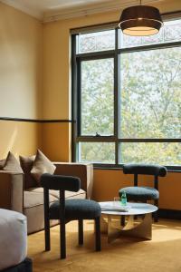 a living room with a couch and two chairs and a table at Hotel Diplomat Sydney in Sydney