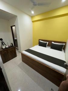 a bedroom with a large bed with a yellow wall at Hotel Elite Enclave in Hyderabad