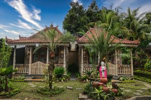 a house in a garden with palm trees at Bongkasa Bali Village Homestay in Ubud