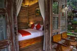 a bedroom with a bed in a wooden house at Bongkasa Bali Village Homestay in Ubud