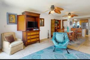 ein Wohnzimmer mit einem TV, einem Stuhl und einem Tisch in der Unterkunft Gulfside Townhome 6 townhouse in Gulf Shores