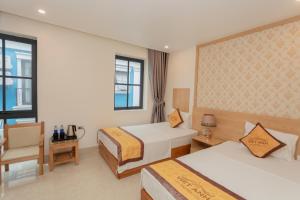 una habitación de hotel con dos camas y una silla en Viet Anh Ha Long Hotel, en Ha Long