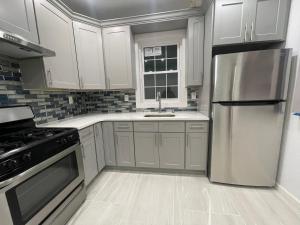a kitchen with white cabinets and a stainless steel refrigerator at Luxury Private room in Queens -30 min to Manhattan in Woodhaven