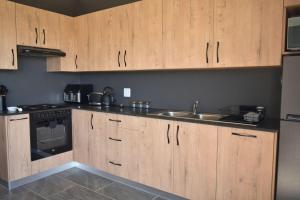 a kitchen with wooden cabinets and a sink at Hartklop Luxury Self Catering Guesthouse in Linkside