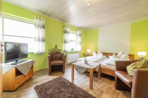 a living room with a bed and a couch and a tv at Pension Gisela in Gößweinstein