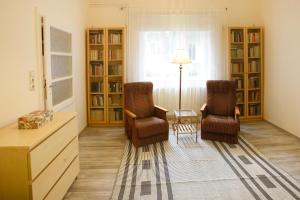 two chairs and a table in a room with book shelves at Harangvirág 36 Vendégház in Verőce