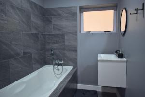 a bathroom with a bath tub and a sink at Hartklop Luxury Self Catering Guesthouse in Linkside +37 photos