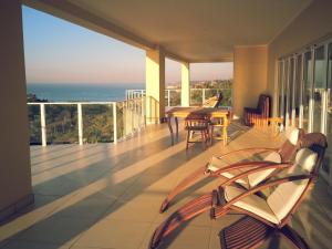 a balcony with a table and chairs and the ocean at The Homestead Margate - South Africa in Margate