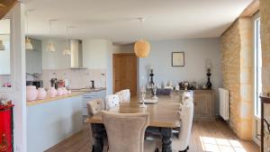 eine Küche und ein Esszimmer mit einem Holztisch und Stühlen in der Unterkunft La Demeure en Périgord Meublé Tourisme 5 étoiles Luxe in Anlhiac