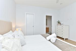 a white bedroom with a white bed and a dresser at Blue Lagoon at Caves Beach Villas in Caves Beach +25 photos