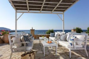a patio with white chairs and tables and the ocean at Artina Nuovo in Marathopoli
