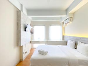 a white bedroom with a white bed and a window at Modern Look and Comfy Studio Patraland Urbano Apartment By Travelio in Bekasi +16 photos