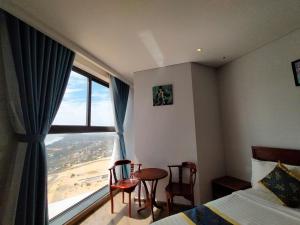 a bedroom with a bed and a window with a table and chairs at Chambay Bliss Retreat Mũi Né in Phan Thiet