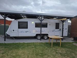 a white rv parked under a tent with a table at Caravan at 36 Clarevale in Clayton North
