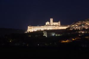 ein großes Gebäude auf einem Hügel in der Nacht in der Unterkunft Casa Vacanze Gaia in Assisi