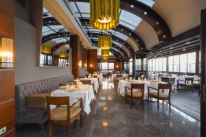 ein Esszimmer mit Tischen, Stühlen und Kronleuchtern in der Unterkunft Tugcan Hotel in Gaziantep