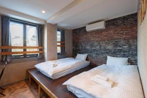 two beds in a room with a brick wall at YAMATO - Doyanen Hotels in Osaka +61 photos
