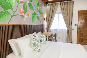 a bedroom with a white bed with flowers on the wall at Casa Mario's in Coron