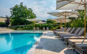 a swimming pool with lounge chairs and umbrellas next to a pool at Andrássy Kúria & Spa in Tarcal