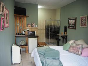 a bedroom with a white bed and a kitchen at Smirna Guesthouse in Vryburg