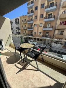 a patio with a table and chairs on a balcony at Comfort 2BR Apartment near Beach & Café del Mar- By HostMT in St Paul's Bay