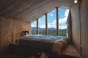 a bedroom with a bed in a room with windows at Earthboat Minakami Hodaigi in Minakami