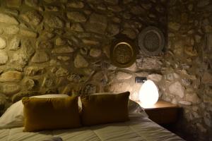 a bedroom with a stone wall with a bed and a lamp at Cal Blasi in Montblanc +65 photos