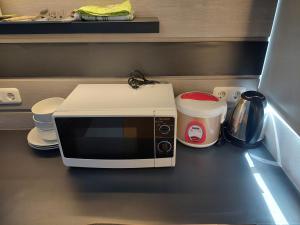 a microwave sitting on top of a kitchen counter at Minimalist Studio Apartment (No Kitchen) at Aeropolis Residence By Travelio in Tangerang +8 photos