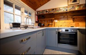 a kitchen with white cabinets and a stove top oven at 345 Ida's Cabin in Trawsfynydd