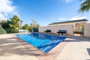 a swimming pool with two benches next to a house at La Marquesa in Camarles
