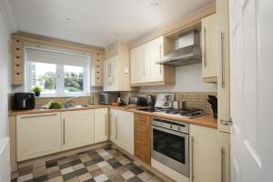 a kitchen with white cabinets and a window at Bay View, Compass Point, Carbis Bay, St Ives in Carbis Bay