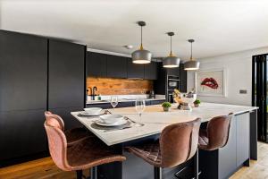 una cocina con armarios negros y una isla blanca con sillas en River Cabin With Mooing, en Remenham