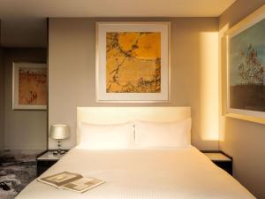 a bedroom with a white bed with a picture on the wall at The Olsen Melbourne Art Series in Melbourne
