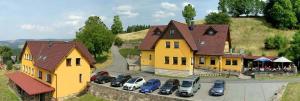a large yellow house with cars parked in a parking lot at Penzion Hamštejn in Koberovy