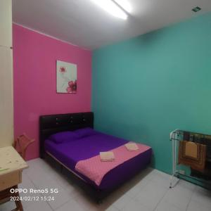 1 dormitorio con cama morada y pared rosa en Al fateh homstay, en Kuah 2 fotos más