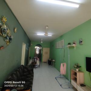 Una sala de estar con paredes verdes y un sofá. en Al fateh homstay, en Kuah