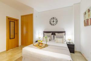 sypialnia z dużym łóżkiem z zegarem na ścianie w obiekcie Living4Malaga The Secret Studio w Maladze