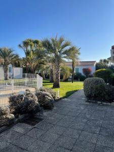 a garden with palm trees and a fence at Le Petit Bois in Sainte-Marie-de-Ré