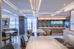 Un restaurante con mesas y sillas y una cocina. en Atour Hotel Guangzhou Zhongcun Hanxi Changlong Metro Station, en Guangzhou 24 fotos más
