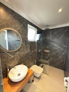 a bathroom with a sink and a toilet and a mirror at Villa Denis Ksamil in Ksamil