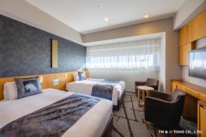 a hotel room with two beds and a flat screen tv at Hotel Gracery Shinjuku in Tokyo