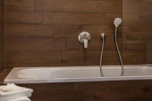 a bath tub with a shower head on a wall at App Lolita in Kühlungsborn