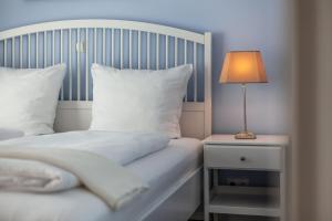 a bed with white sheets and a lamp on a night stand at App Lolita in Kühlungsborn
