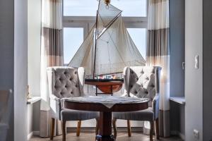 a room with two chairs and a table with a sail on the window at App Lolita in Kühlungsborn