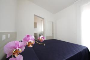 two purple orchids sitting on top of a bed at Residence Città Ideale in Urbino