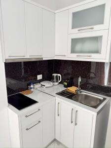 a white kitchen with a sink and a microwave at Villa Denis Ksamil in Ksamil