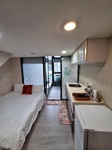 ein kleines Schlafzimmer mit einem Bett und einer Küche in der Unterkunft Love溫泉湯宿 in Jiaoxi
