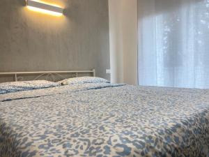 a bedroom with a bed with a blue comforter and a window at Suite Emilia 4 in Bologna