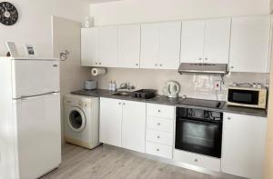 a kitchen with white cabinets and a washer and dryer at Theodoros Apt.79 in Paralimni