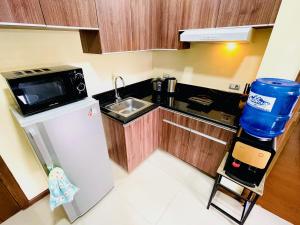 a small kitchen with a sink and a refrigerator at Azalea 1BR Suite - Pool, Gym, WiFi, Netflix, AC, Kitchen, Ayala Mall in Cebu City